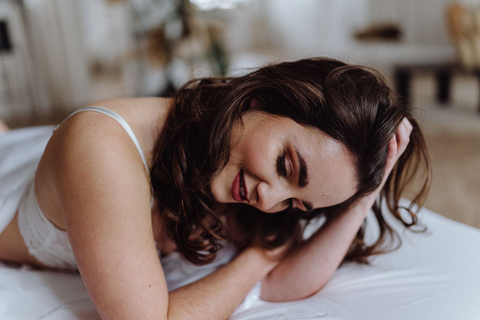 Sarah liegt lachend auf dem Bett, die Hand im Haar