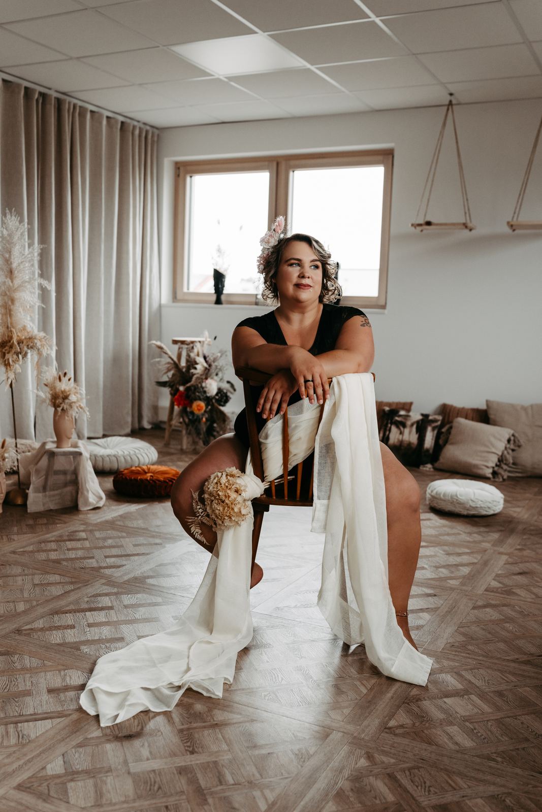 Sarah sitzt mit Blumen und weißem Tuch auf einem Stuhl im Studio
